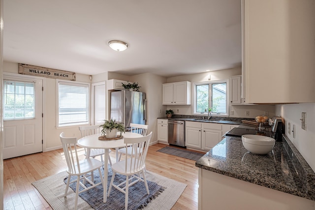 kitchen featuring a sink, baseboards, light wood-style floors, stainless steel appliances, and white cabinetry