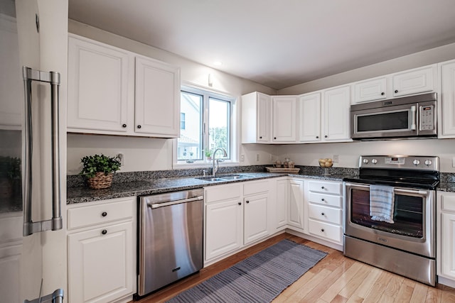 kitchen with a sink, light wood finished floors, stainless steel appliances, recessed lighting, and white cabinetry