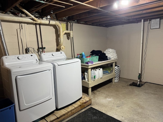 clothes washing area with washing machine and clothes dryer, laundry area, and concrete block wall