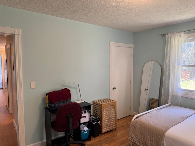 bedroom with a textured ceiling and wood finished floors