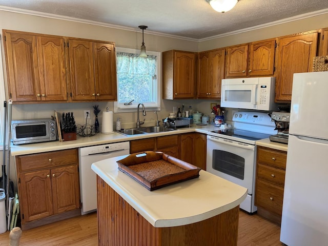kitchen featuring light wood finished floors, a sink, brown cabinetry, and white appliances
