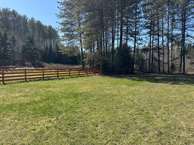 view of yard featuring a wooded view and fence