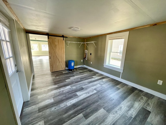 unfurnished room featuring dark wood-style flooring, a barn door, and plenty of natural light