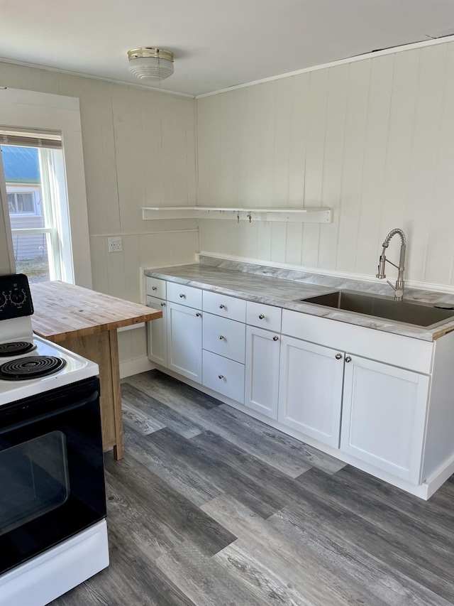 kitchen with a sink, dark wood-style flooring, white cabinetry, range with electric stovetop, and wooden counters