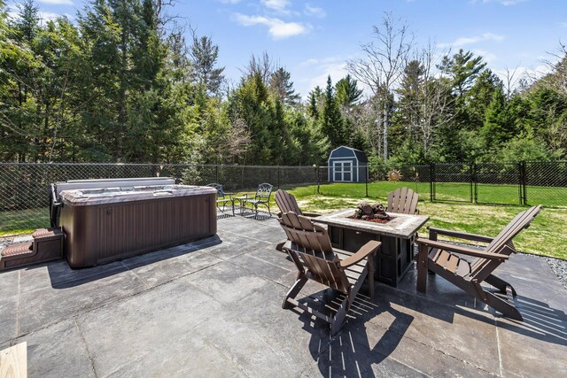 35 Graystone Dr, Hampden, ME 04444 - view of patio / terrace featuring a storage shed, a hot tub, an outdoor structure, a fenced backyard, and an outdoor fire pit