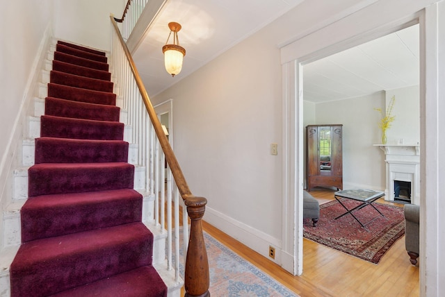11 Linden St, Bath, ME 04530 - staircase featuring baseboards, a fireplace, and wood finished floors