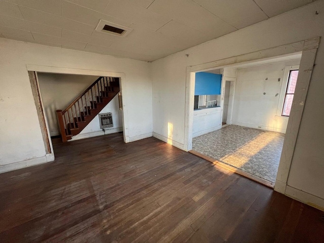 unfurnished living room featuring visible vents, stairway, baseboards, wood-type flooring, and heating unit