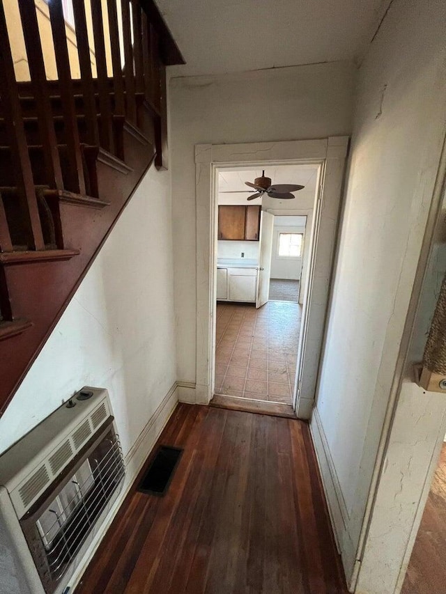 corridor featuring baseboards, heating unit, visible vents, and hardwood / wood-style flooring