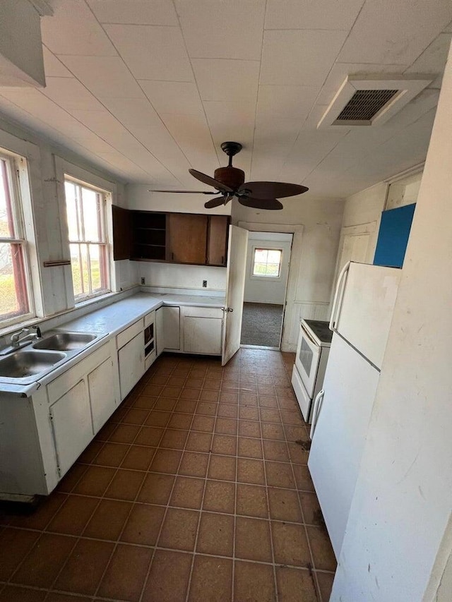 kitchen featuring open shelves, a sink, light countertops, freestanding refrigerator, and visible vents