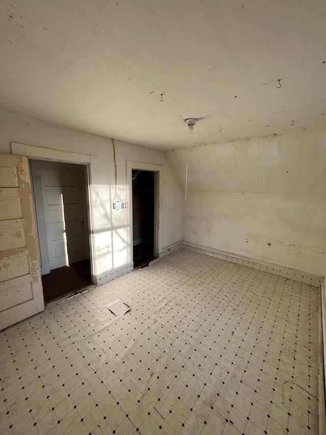 spare room with light floors and vaulted ceiling
