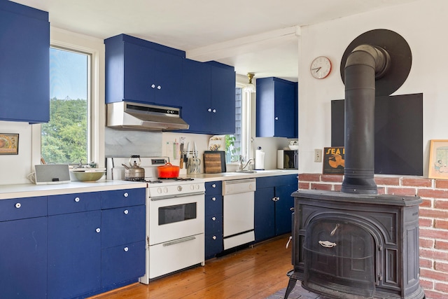 651 N Shore Rd, North Haven, ME 04853 - kitchen featuring under cabinet range hood, a wood stove, white appliances, blue cabinetry, and hardwood / wood-style floors