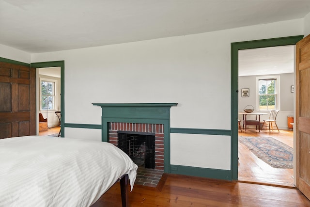 651 N Shore Rd, North Haven, ME 04853 - bedroom featuring multiple windows, a fireplace, wood finished floors, and baseboards