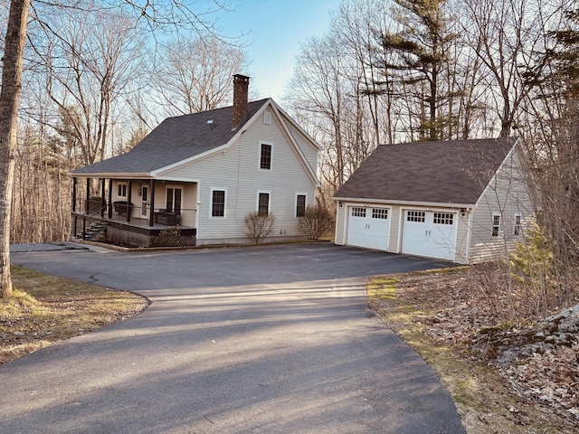 view of home's exterior featuring an outdoor structure, a garage, covered porch, roof with shingles, and a chimney