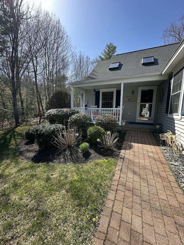 doorway to property featuring covered porch and roof with shingles