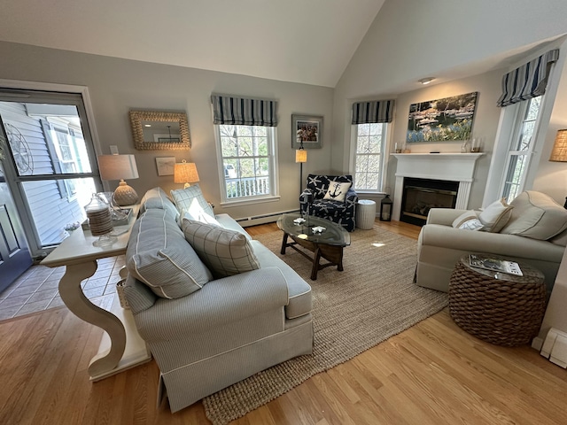 living area with a glass covered fireplace, a baseboard radiator, wood finished floors, and lofted ceiling