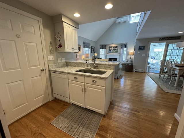 kitchen with a peninsula, open floor plan, a baseboard radiator, a sink, and dishwasher