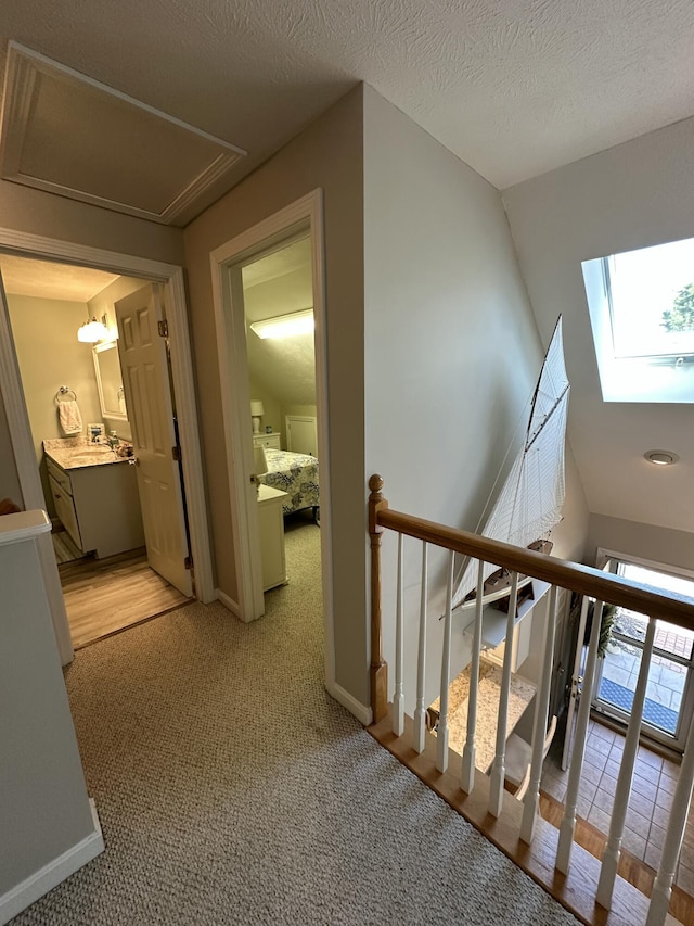 hall with a skylight, baseboards, and an upstairs landing