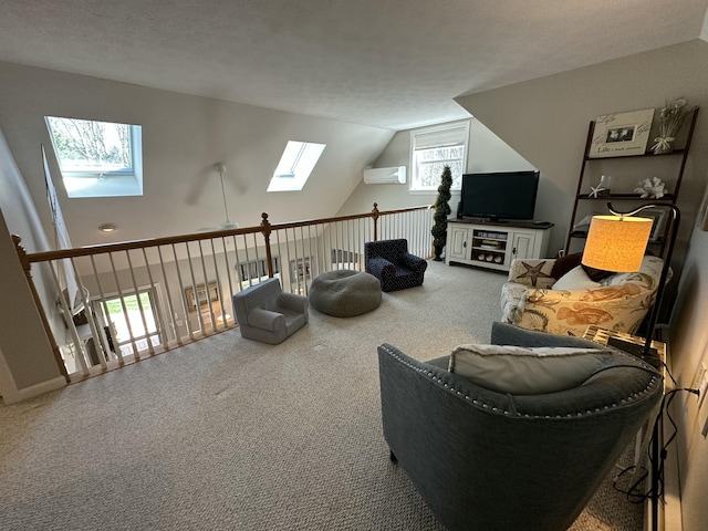 carpeted living area with a ceiling fan, a wall mounted AC, and lofted ceiling with skylight