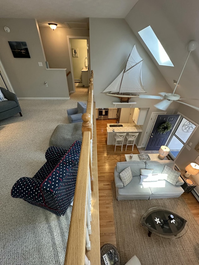 living area with baseboards, lofted ceiling with skylight, and wood finished floors