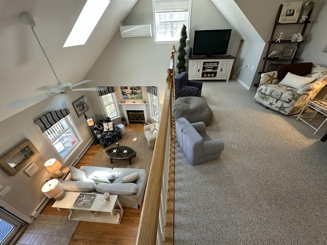 living room with a skylight, plenty of natural light, high vaulted ceiling, and a baseboard radiator