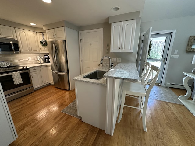 kitchen featuring a sink, white cabinetry, appliances with stainless steel finishes, and a peninsula