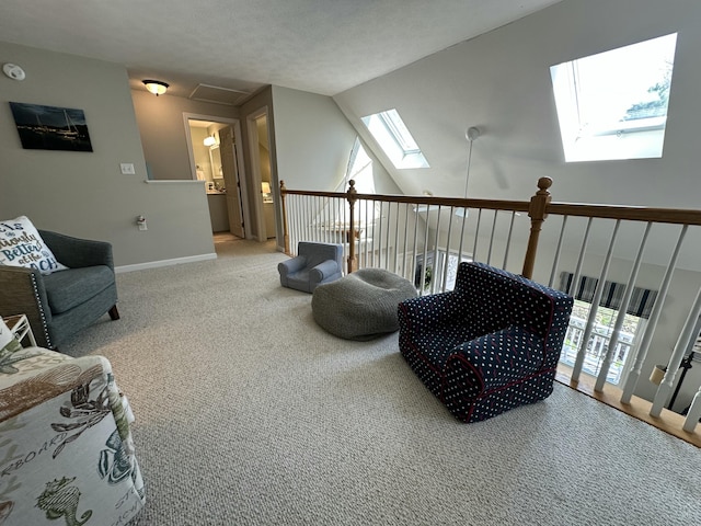 sitting room with carpet floors, baseboards, and vaulted ceiling with skylight