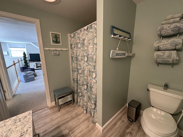 full bathroom featuring toilet, baseboards, curtained shower, and wood finished floors