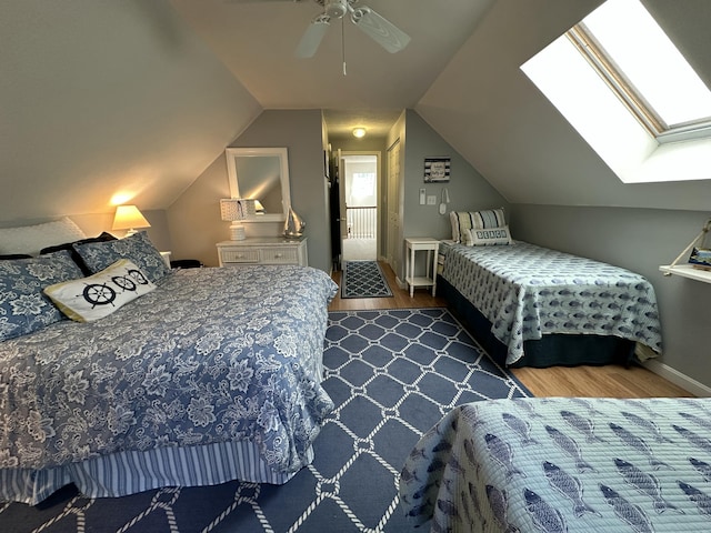 bedroom with baseboards, ceiling fan, lofted ceiling with skylight, and wood finished floors
