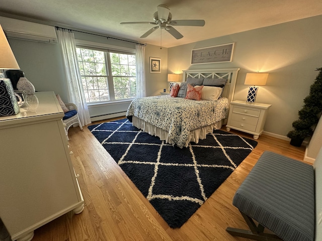 bedroom featuring an AC wall unit, a baseboard radiator, light wood finished floors, and baseboards