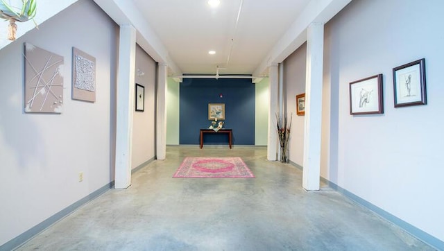 hallway featuring finished concrete floors, baseboards, and recessed lighting
