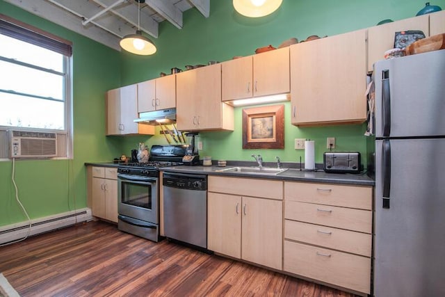 kitchen with under cabinet range hood, a sink, dark countertops, appliances with stainless steel finishes, and dark wood-style floors
