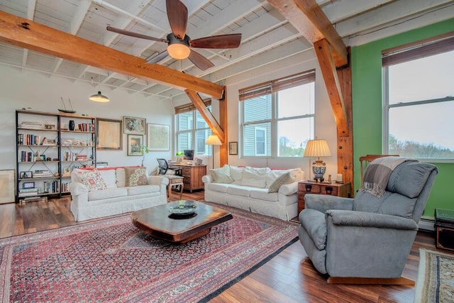 living area with beamed ceiling, a baseboard radiator, ceiling fan, and wood finished floors