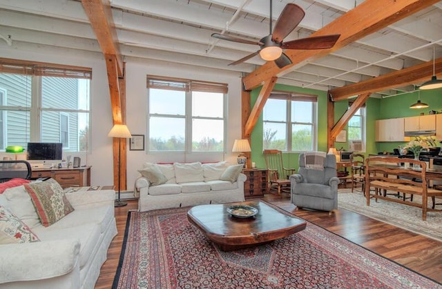 living area with a wealth of natural light, a ceiling fan, baseboard heating, and wood finished floors