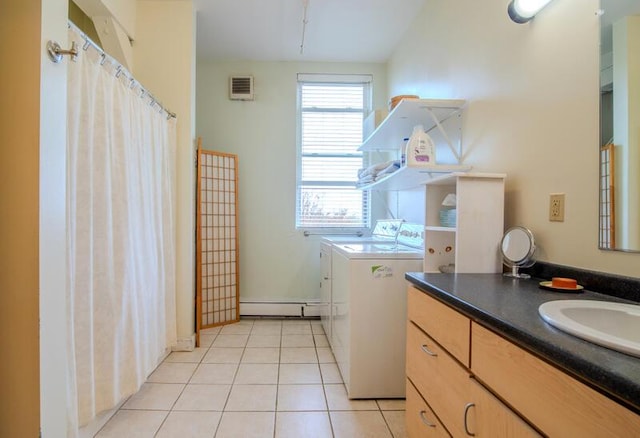 laundry area with baseboard heating, light tile patterned floors, visible vents, washing machine and clothes dryer, and laundry area