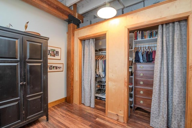 bedroom with beam ceiling, wood finished floors, baseboards, and multiple closets