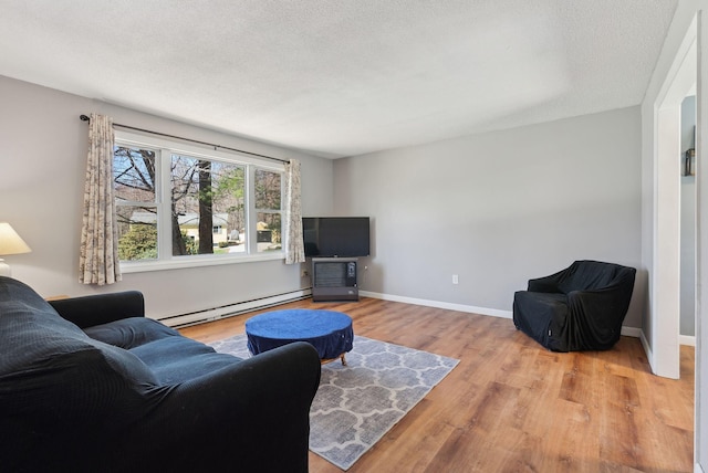 living area featuring baseboards, a baseboard heating unit, and light wood finished floors