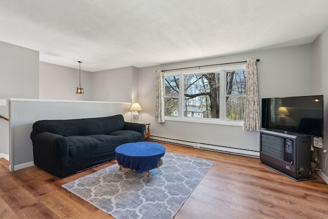 living room featuring a textured ceiling, a baseboard heating unit, and wood finished floors
