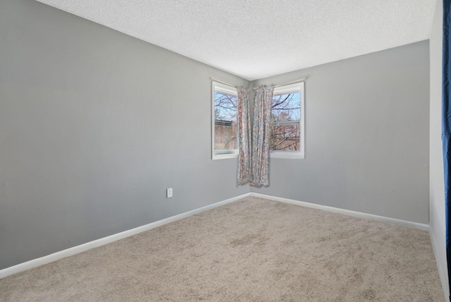 carpeted empty room with a textured ceiling and baseboards
