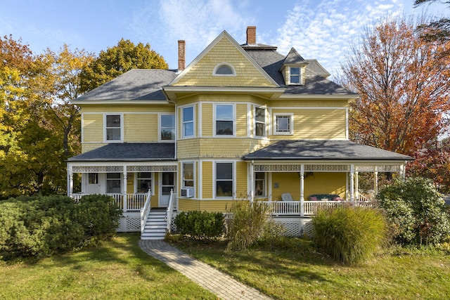 victorian home featuring a porch, a shingled roof, a front lawn, and a chimney