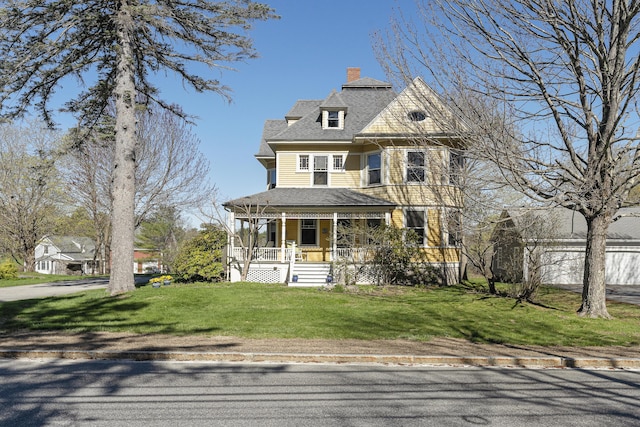 victorian home featuring covered porch, a chimney, roof with shingles, and a front lawn