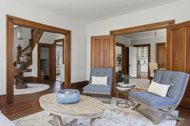 living area with stairs, baseboards, and wood finished floors