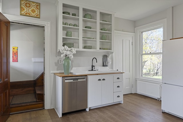 kitchen with stainless steel dishwasher, freestanding refrigerator, radiator, light countertops, and white cabinets