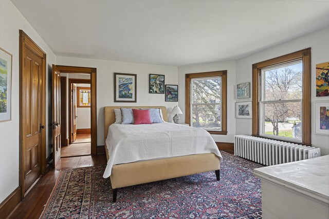 bedroom featuring radiator heating unit, baseboards, and dark wood-style floors