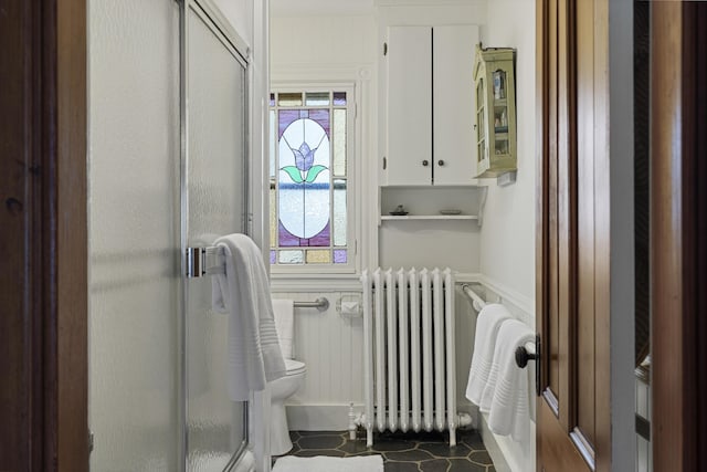 full bathroom featuring wainscoting, radiator heating unit, toilet, and a shower stall