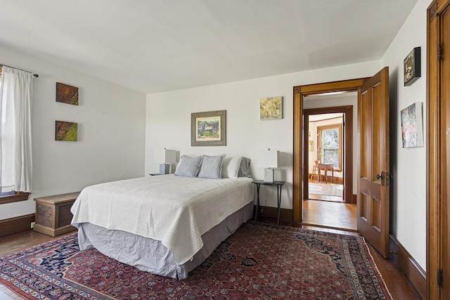 bedroom featuring dark wood-style flooring, baseboards, and multiple windows