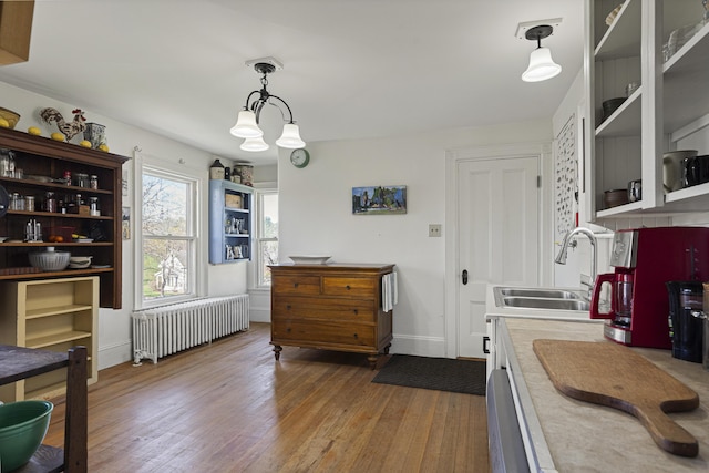 kitchen with open shelves, wood finished floors, radiator heating unit, light countertops, and a sink