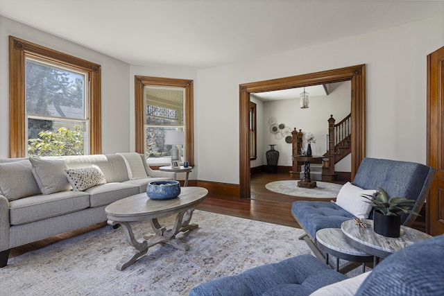 living area with baseboards, wood finished floors, and stairway