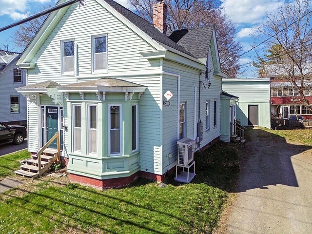exterior space with entry steps, a chimney, ac unit, and roof with shingles