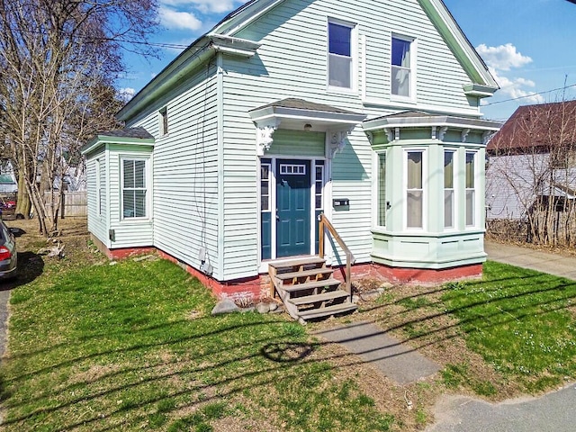 view of front of home with a front yard, fence, and entry steps