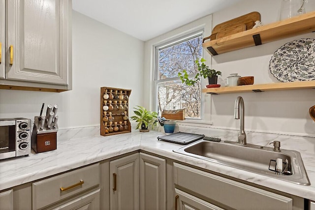 kitchen featuring a sink, open shelves, a toaster, and gray cabinetry